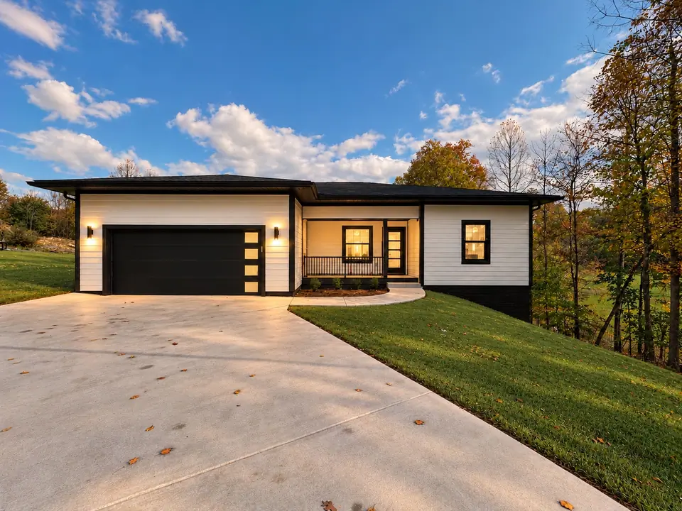 Front of 202 King Drive with white siding, black garage door, covered front porch and concrete driveway