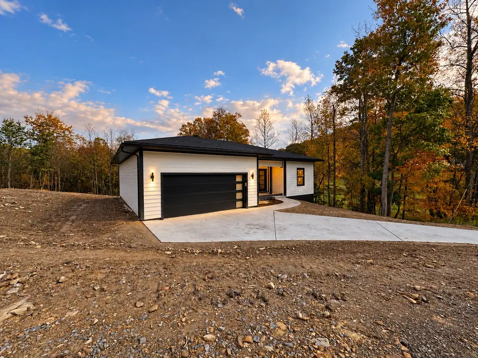 Wide view of the front of 202 King Drive across graded gravel ground, with garage and driveway