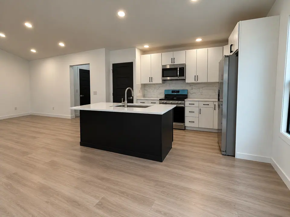 Open kitchen at 202 King Drive with black island, white cabinets and stainless steel appliances