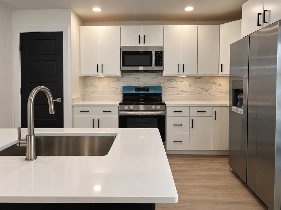 Kitchen sink island with white cabinets, range and stainless steel refrigerator