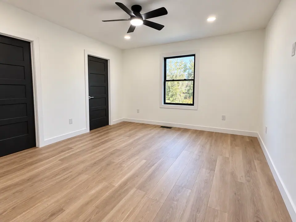 Bedroom with ceiling fan, window and two black doors