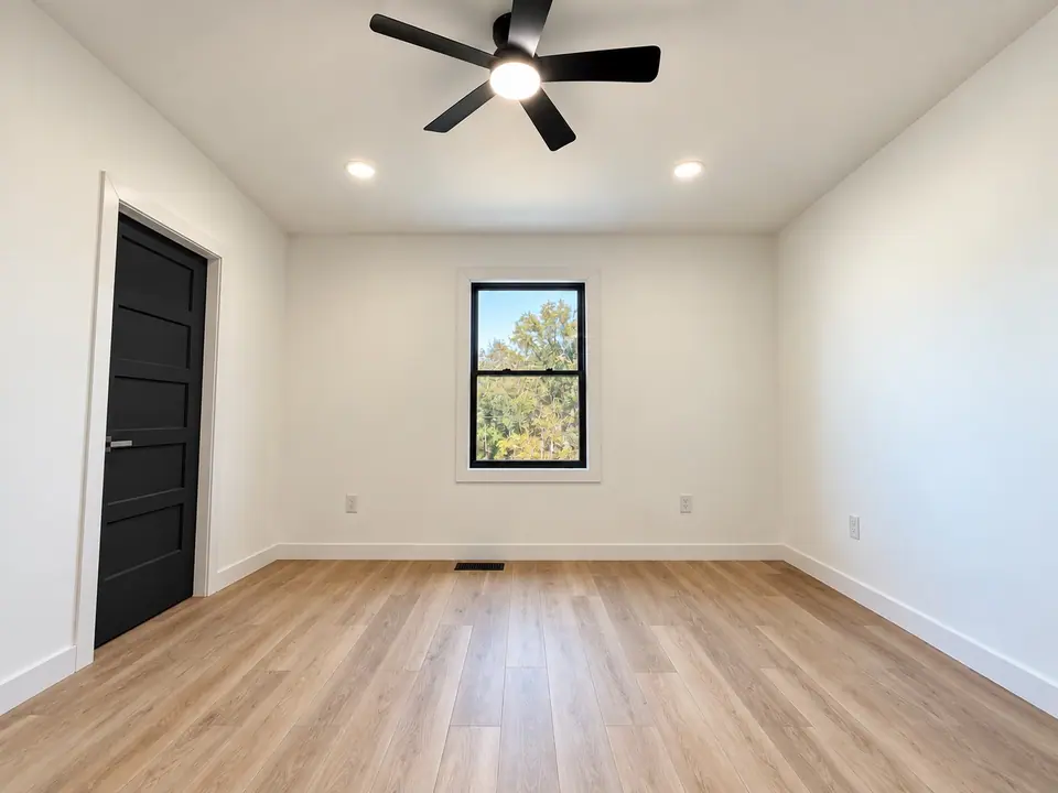 Bedroom with ceiling fan, window and black door